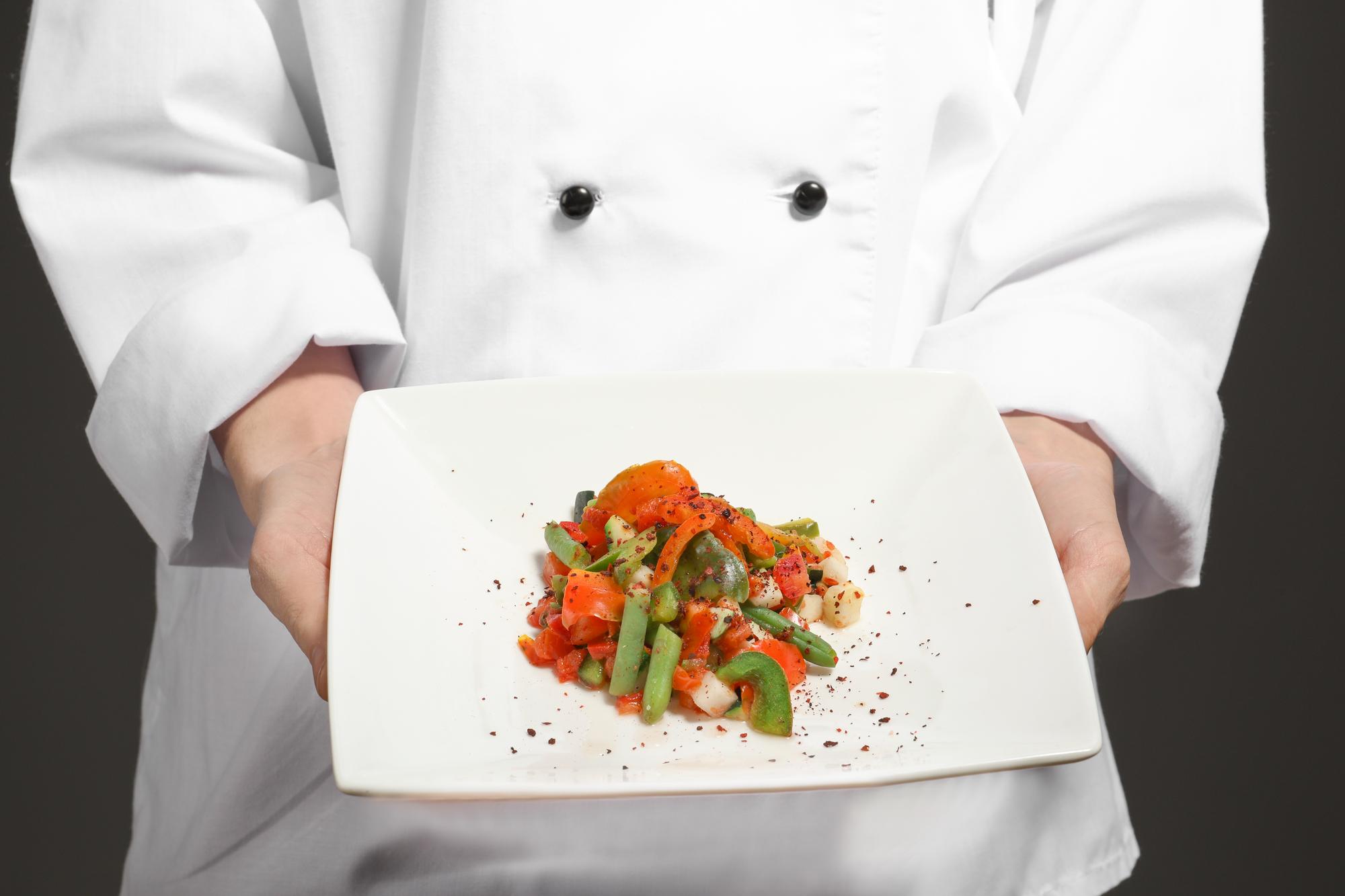 Chef mostrando un plato colorido en cocina moderna